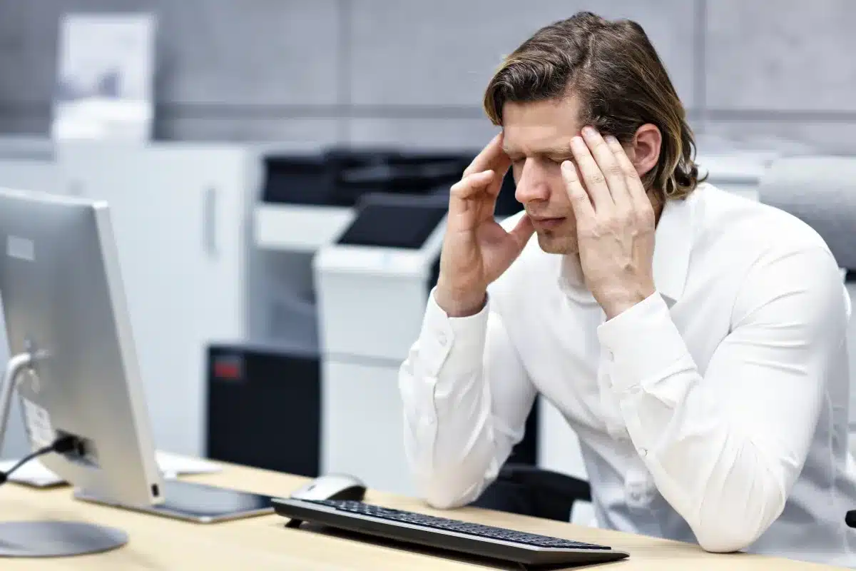 Close up portrait of businessman with headache t workplace