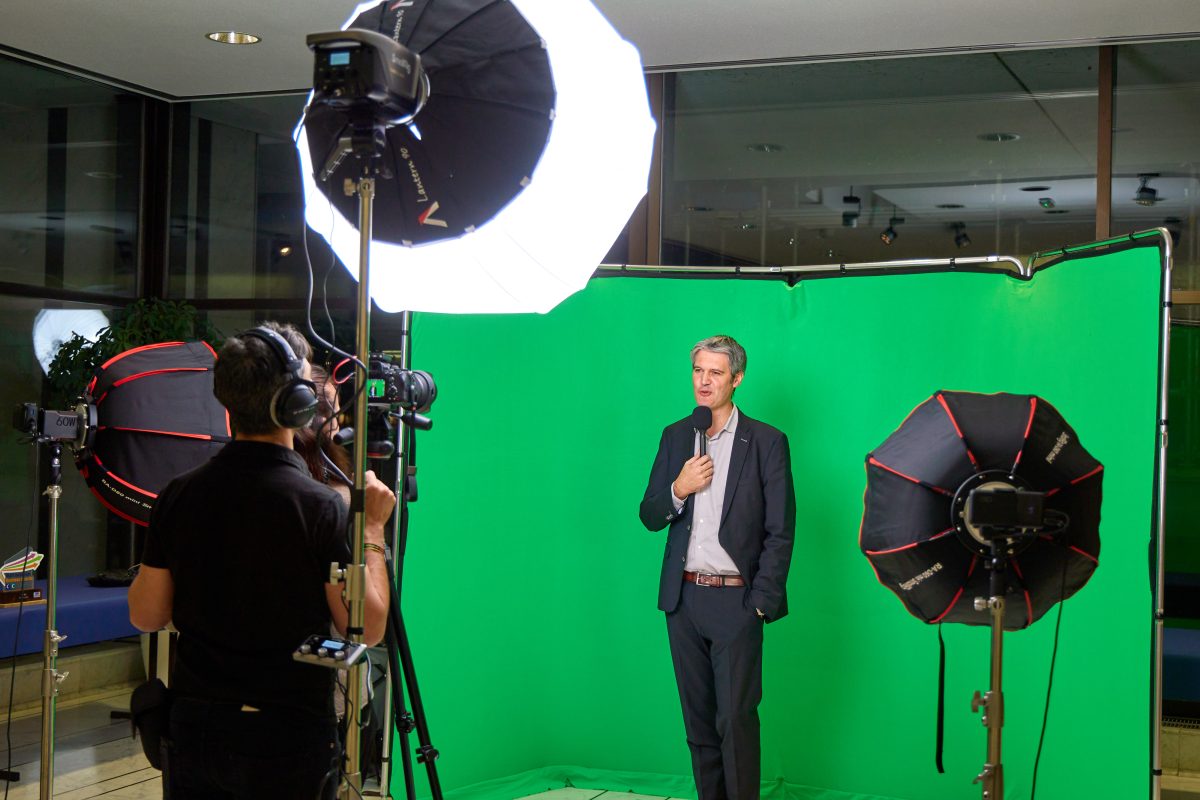Intervenant micro en main sur un plateau fond vert éclairé par des softbox