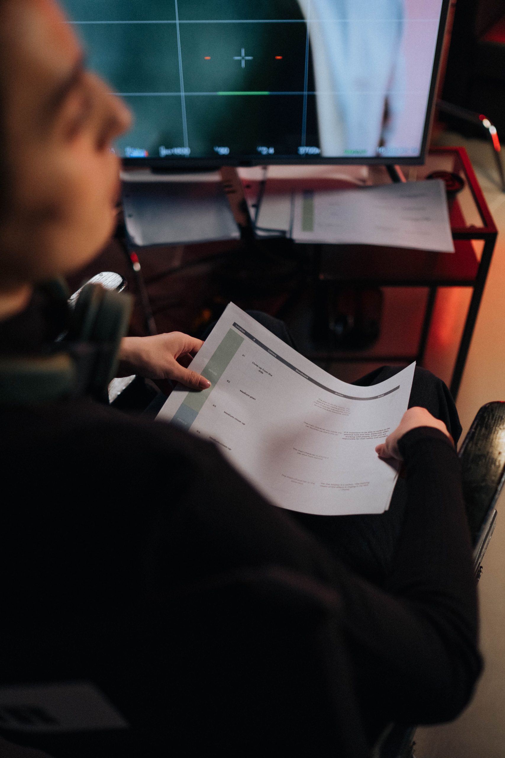 Membre d’une équipe audiovisuelle consultant un script devant un moniteur