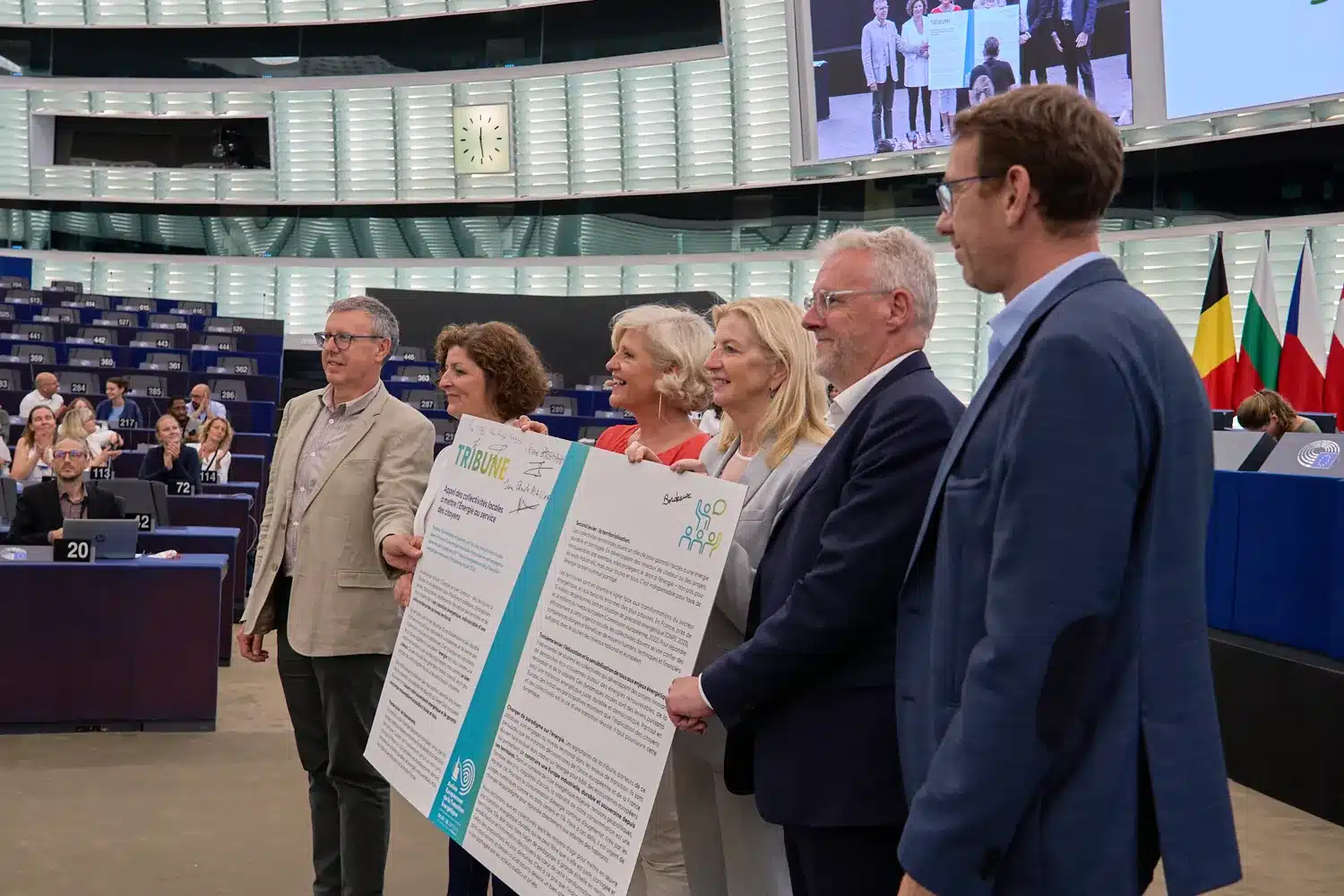 Intervenants présentant le plaidoyer signé dans l’hémicycle du Parlement européen à Strasbourg, devant les drapeaux des États membres, lors de la clôture des Assises européennes de la transition énergétique 2025